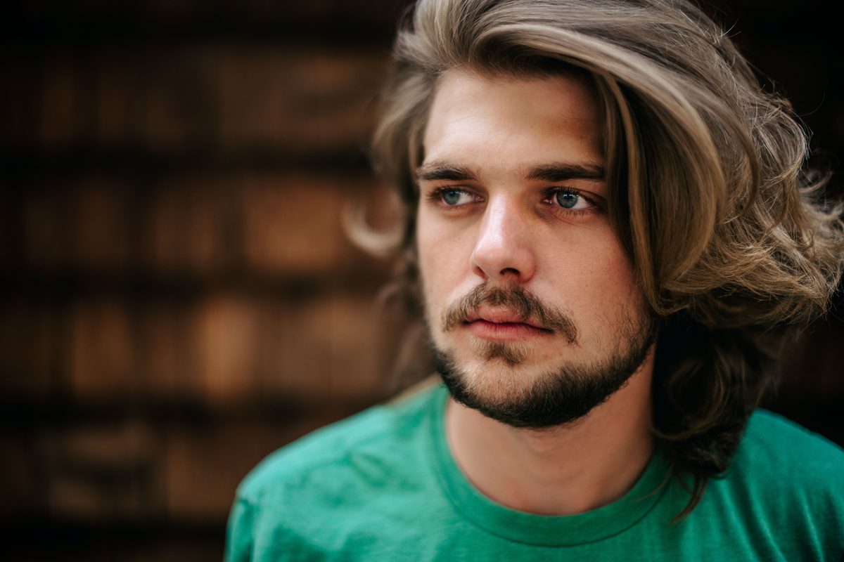 Thoughtful long hair beard hairstyle shown on a young man.