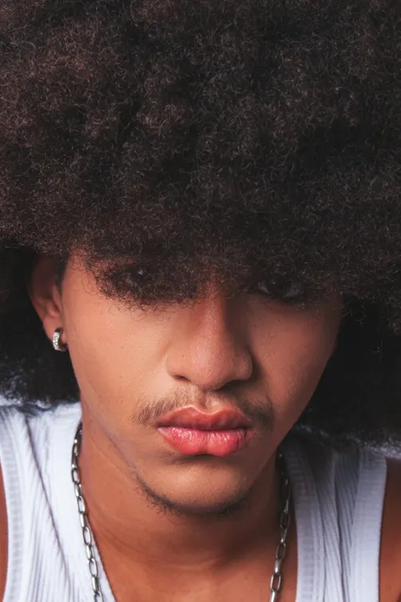 A young man with coily afro-textured hair in a close-up portrait.