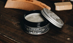 Pomade for a burst fade: open pomade tin beside a wooden comb