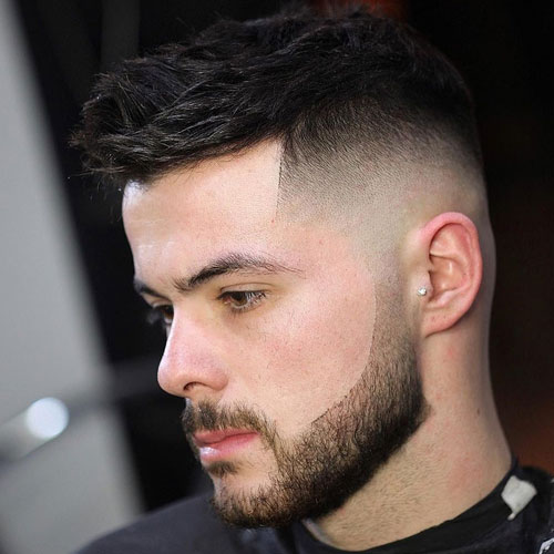 Man with a sharp high skin fade haircut and full beard