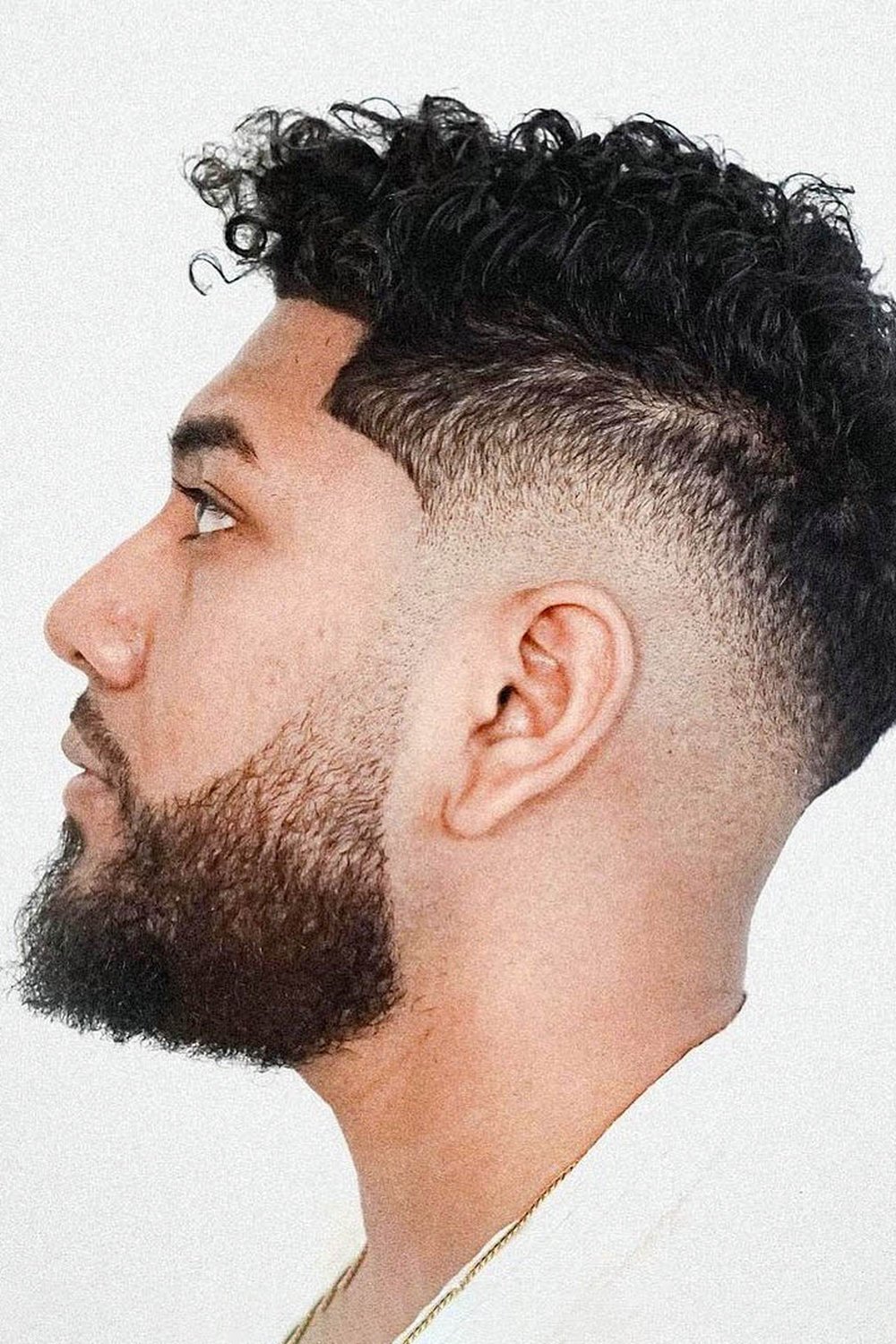 High taper fade framing a full curly top, sides faded tight from the temples down