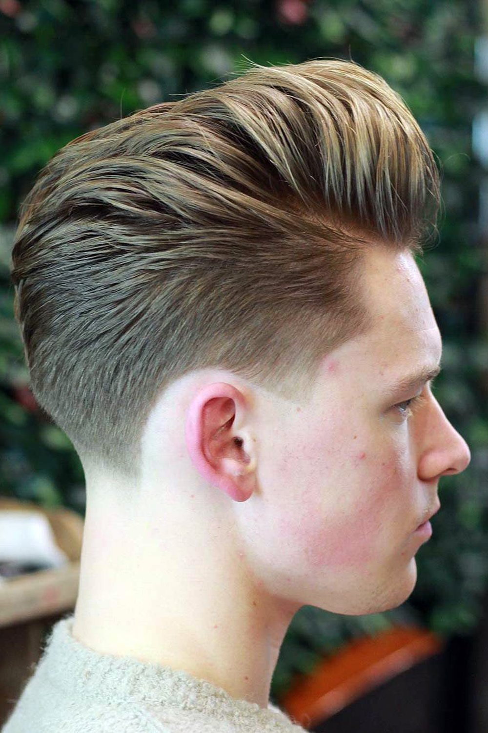 Blonde pompadour swept up and back with a clean tapered fade, side view