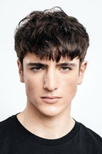 Teenage boy with a textured fringe and burst fade — choppy fringe over faded sides