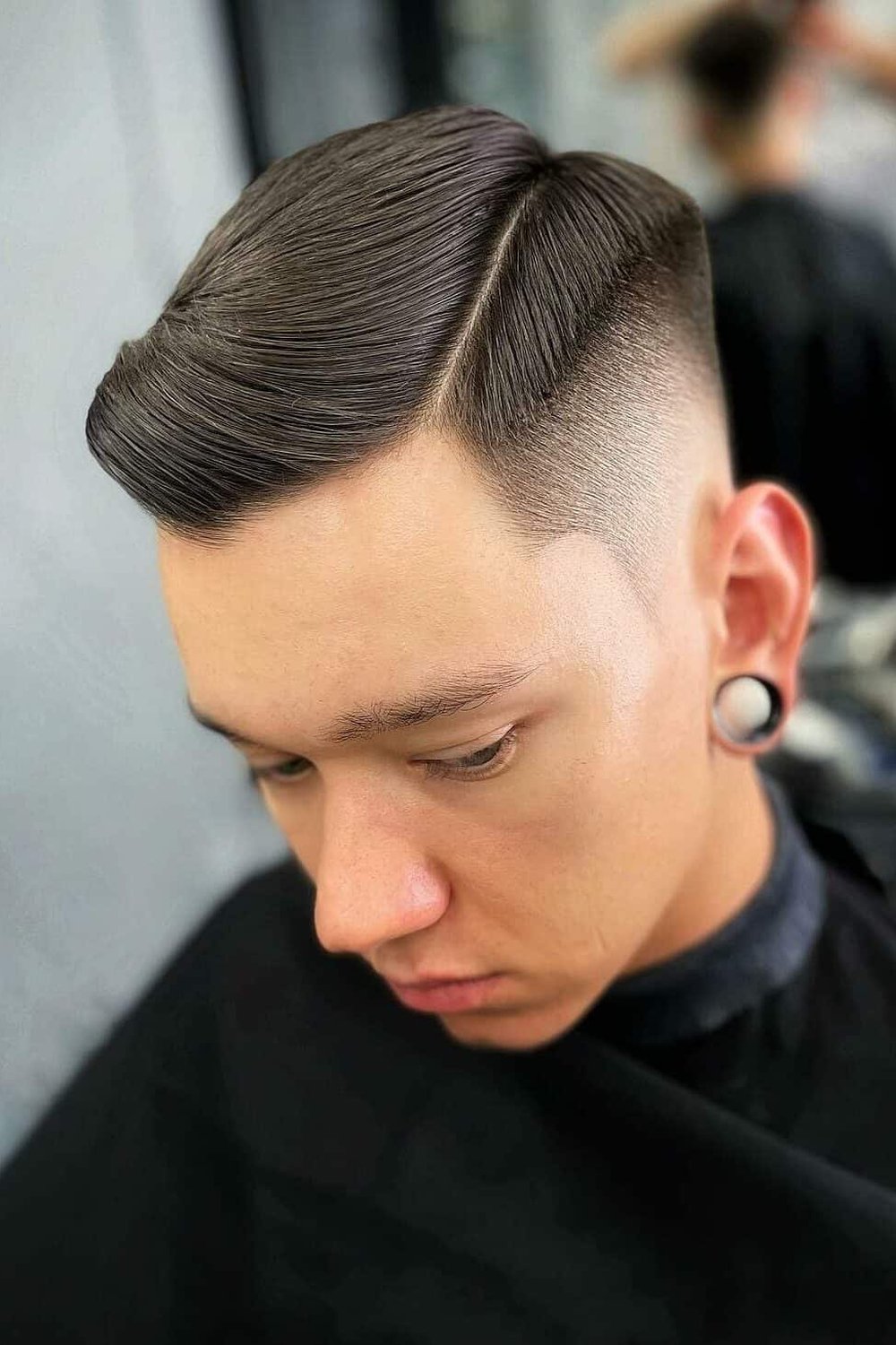 Man with a hard-part taper fade — clean shaved part line and crisp taper