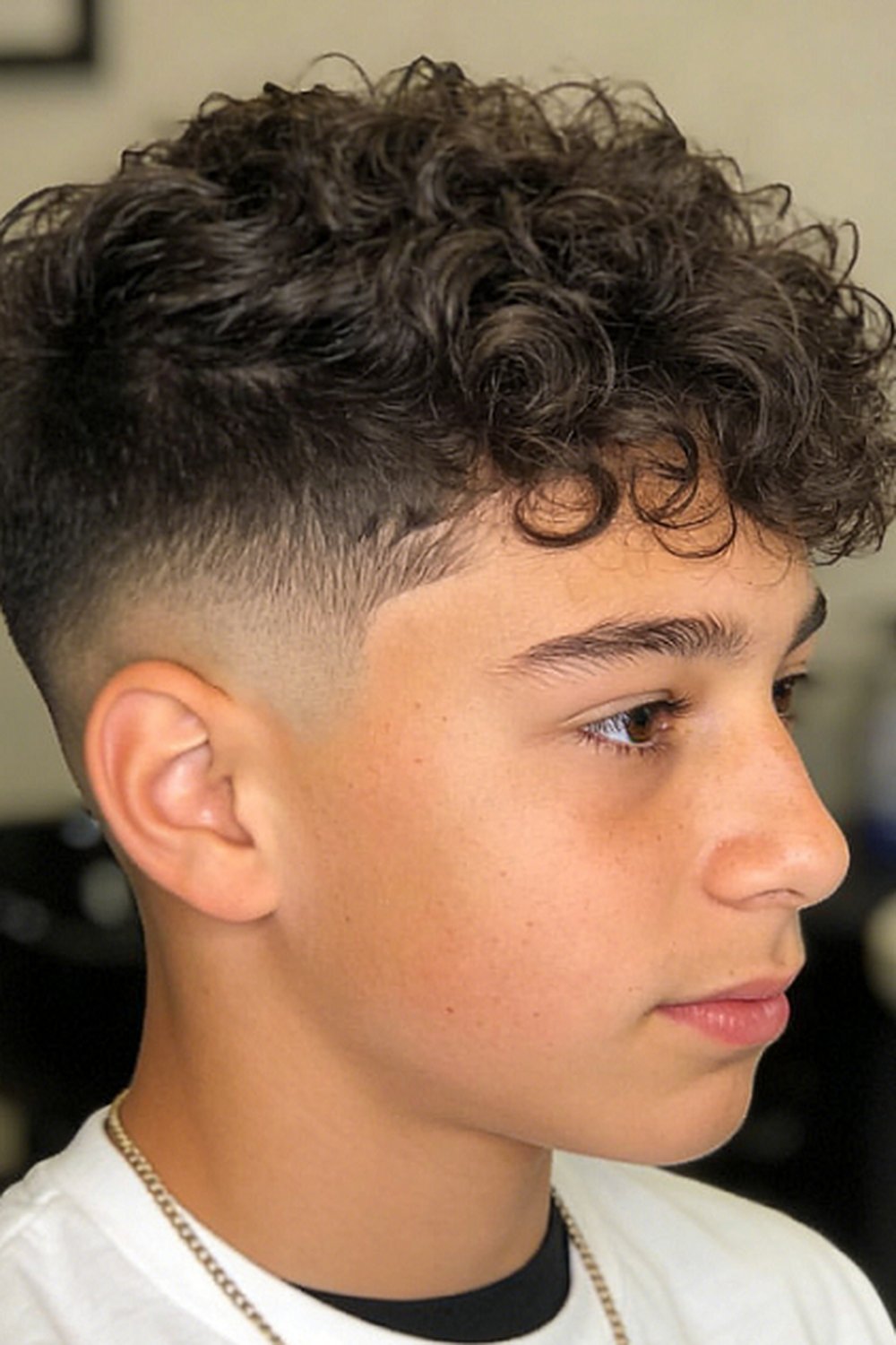 Teen boy with a curly-top burst fade — tight curls above a clean faded arc