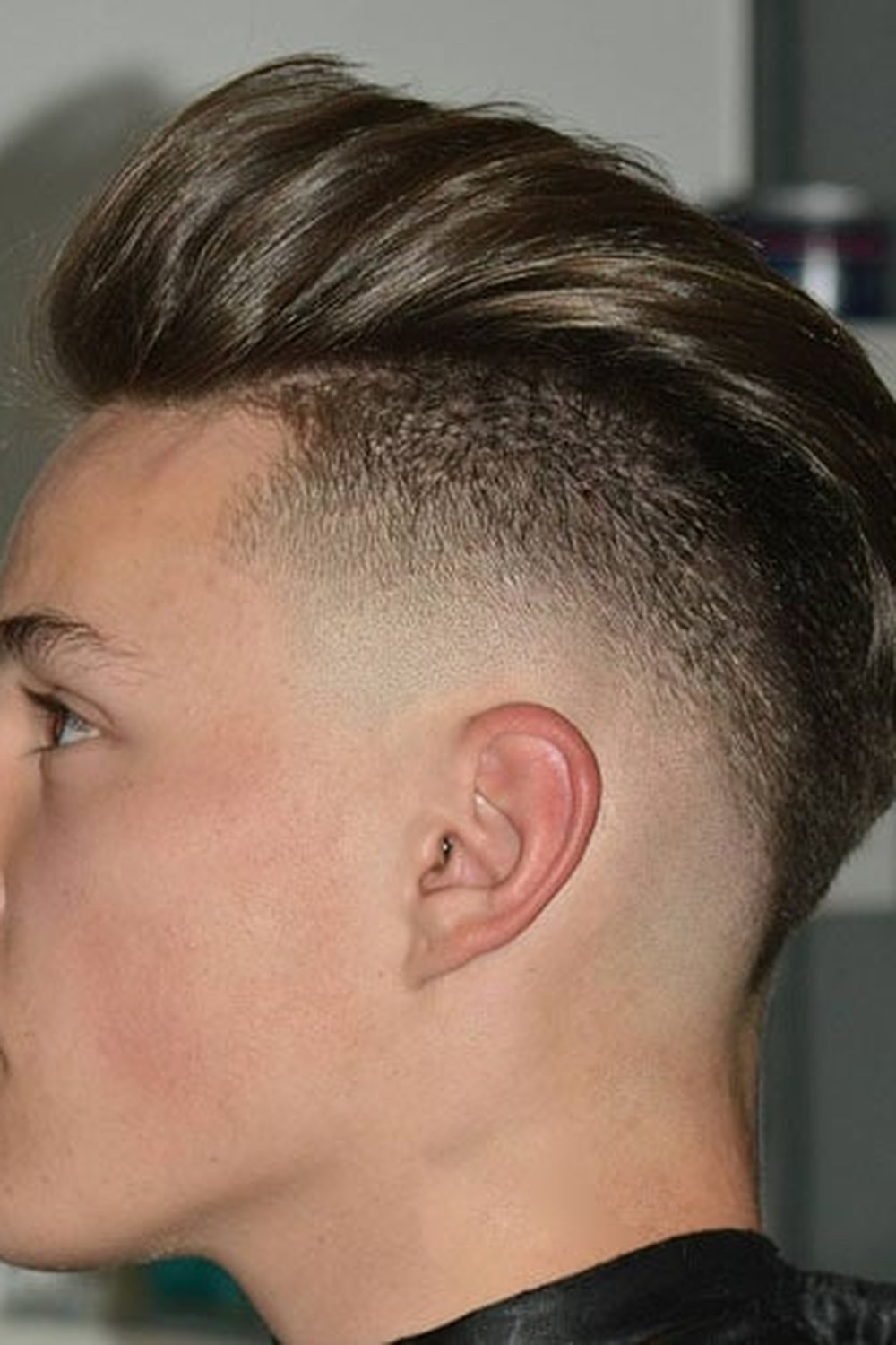 Teenager with a faux hawk burst fade — swept-up top over a faded curve around the ear