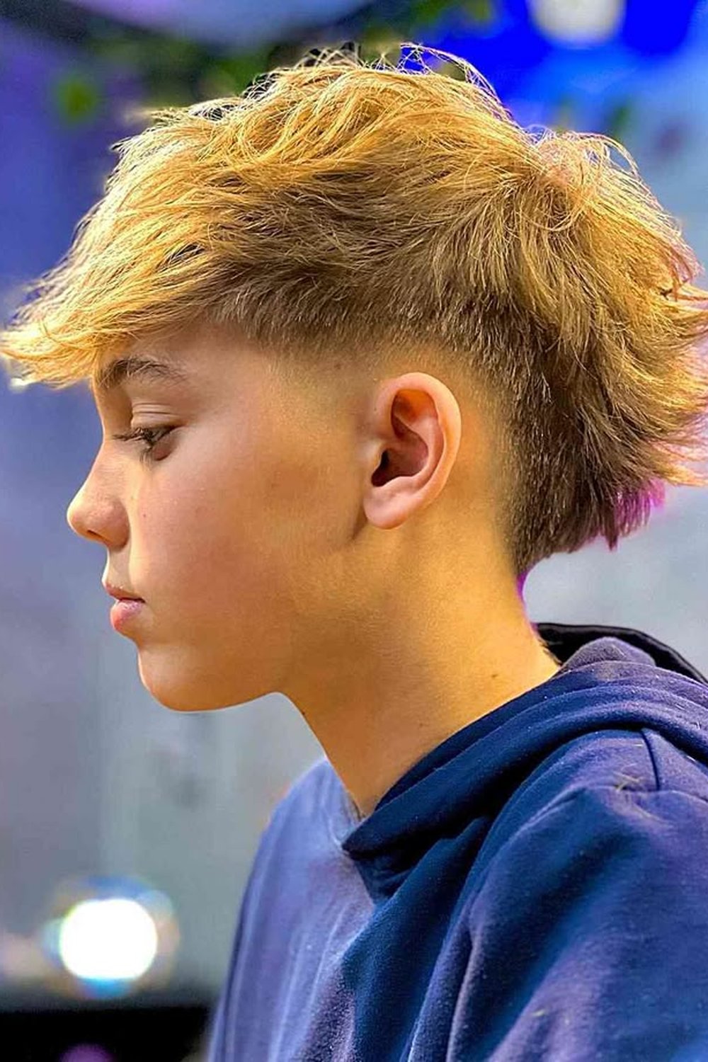 Blonde boy with a burst fade mullet — longer textured hair at the back with faded sides