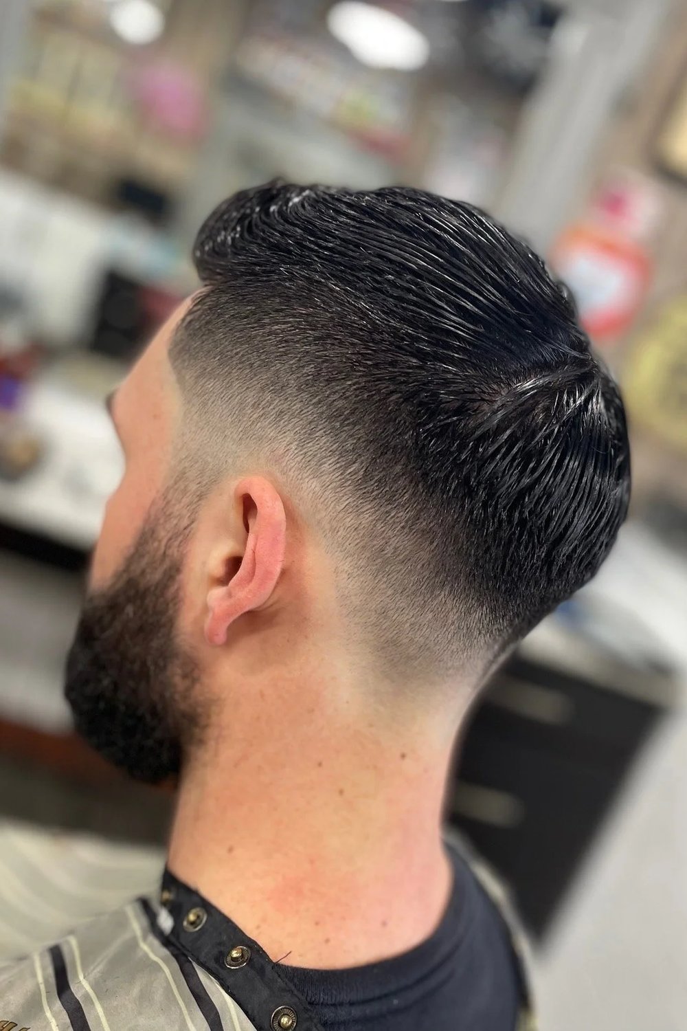 Back-side view of a comb-over haircut with a low drop fade curving around the ear