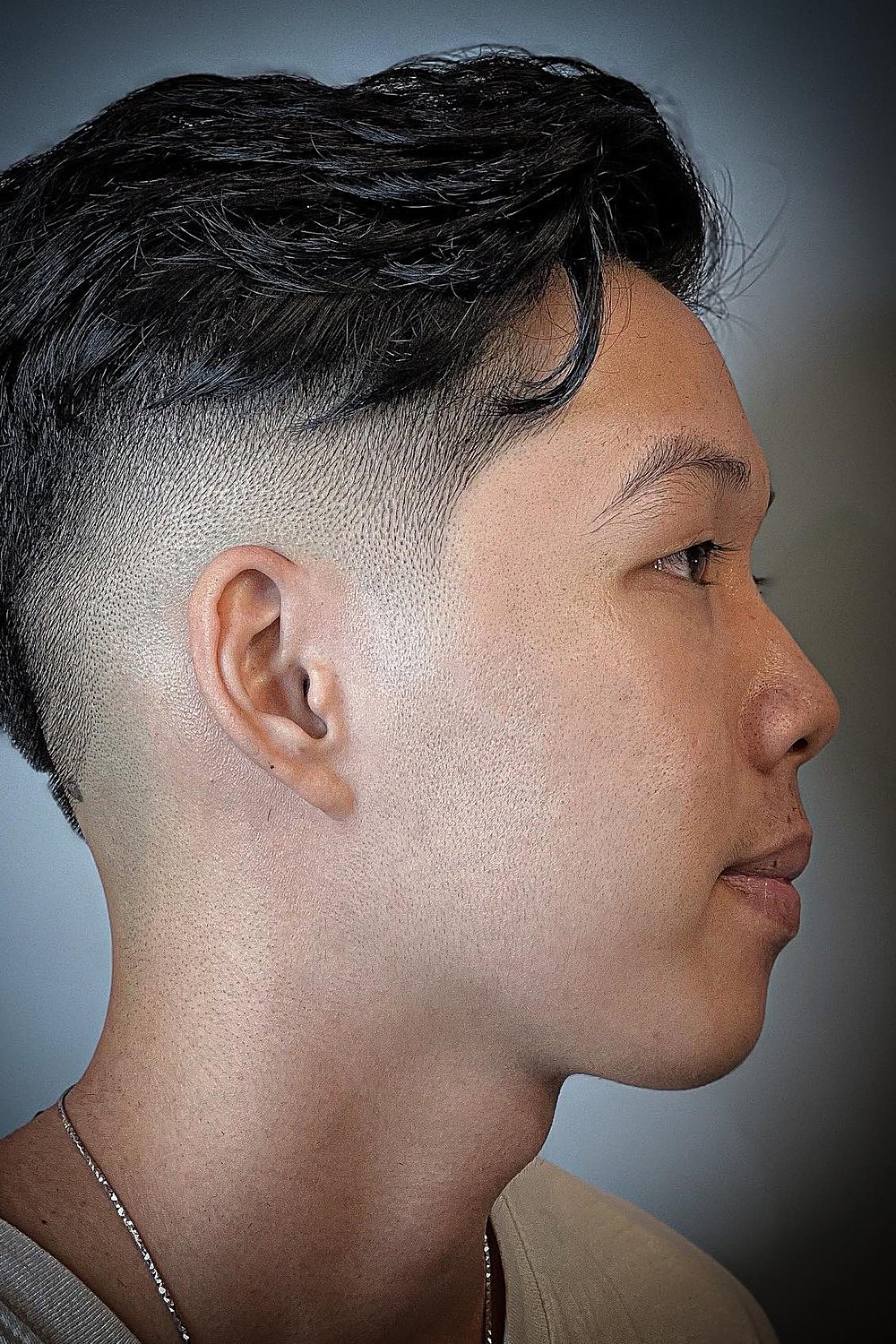 Young man with a short textured curtain and drop taper — choppy middle part with a curved drop fade around the ear