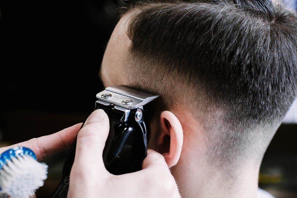 Barber using a clipper to refine a close fade