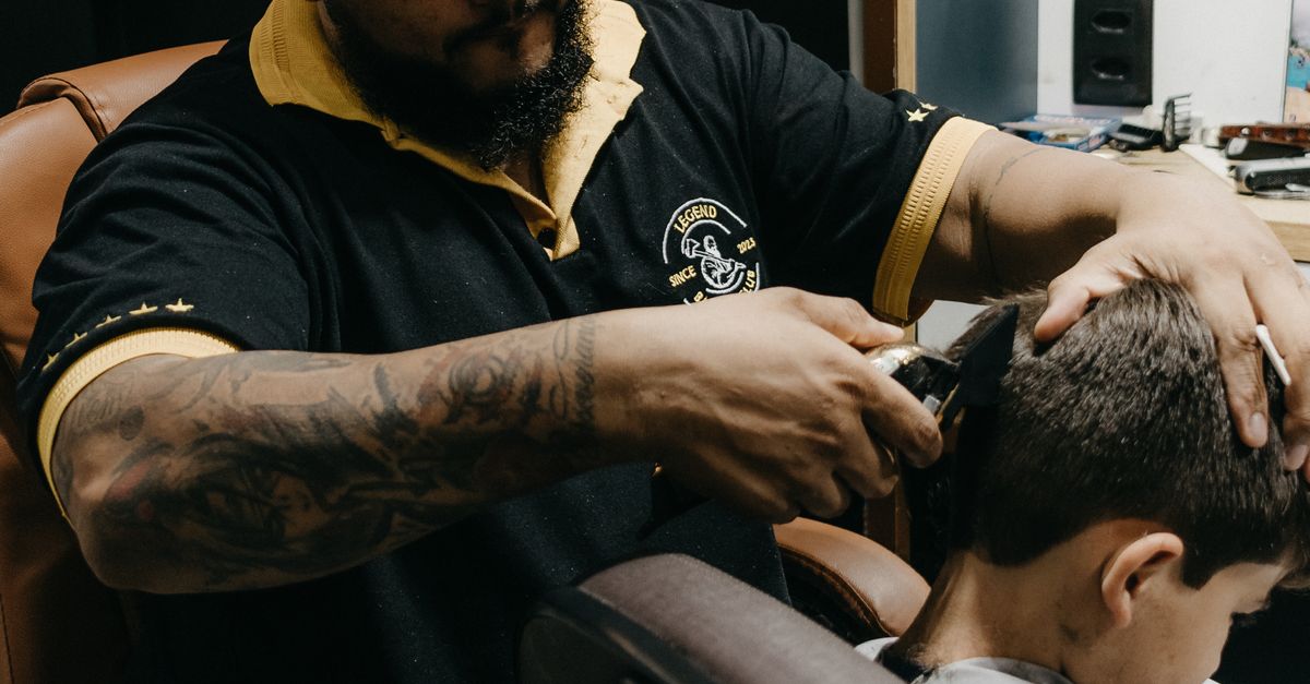 Barber trimming a little boy’s side hair