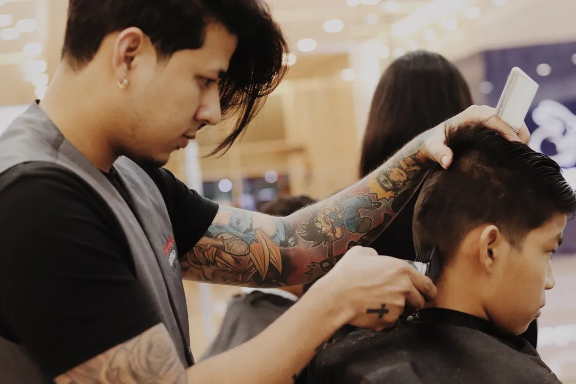 Barber using clippers on a boy’s haircut