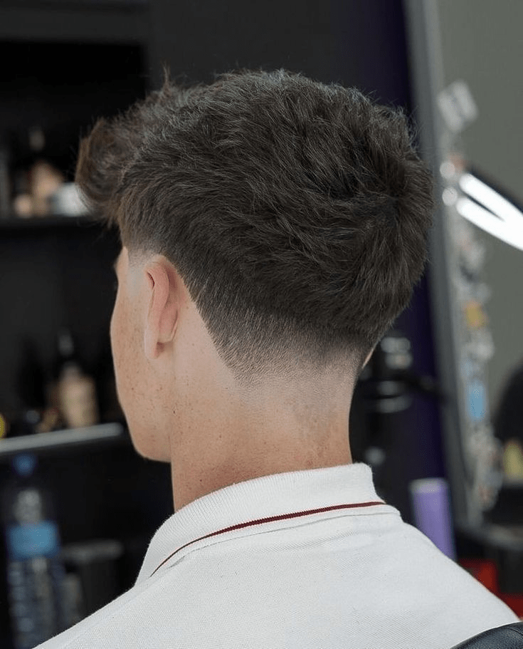 Rear view showing a low taper fading cleanly into the neckline beneath a quiff top.