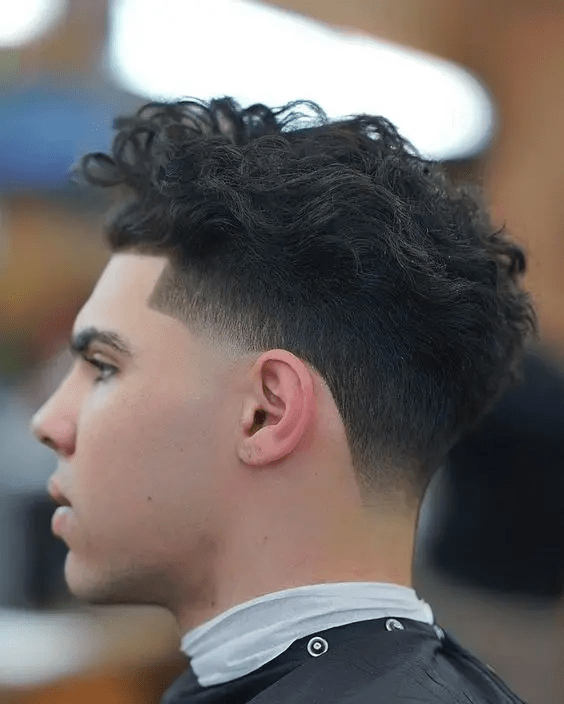 Curly top with a low taper fade around the ears and neckline.